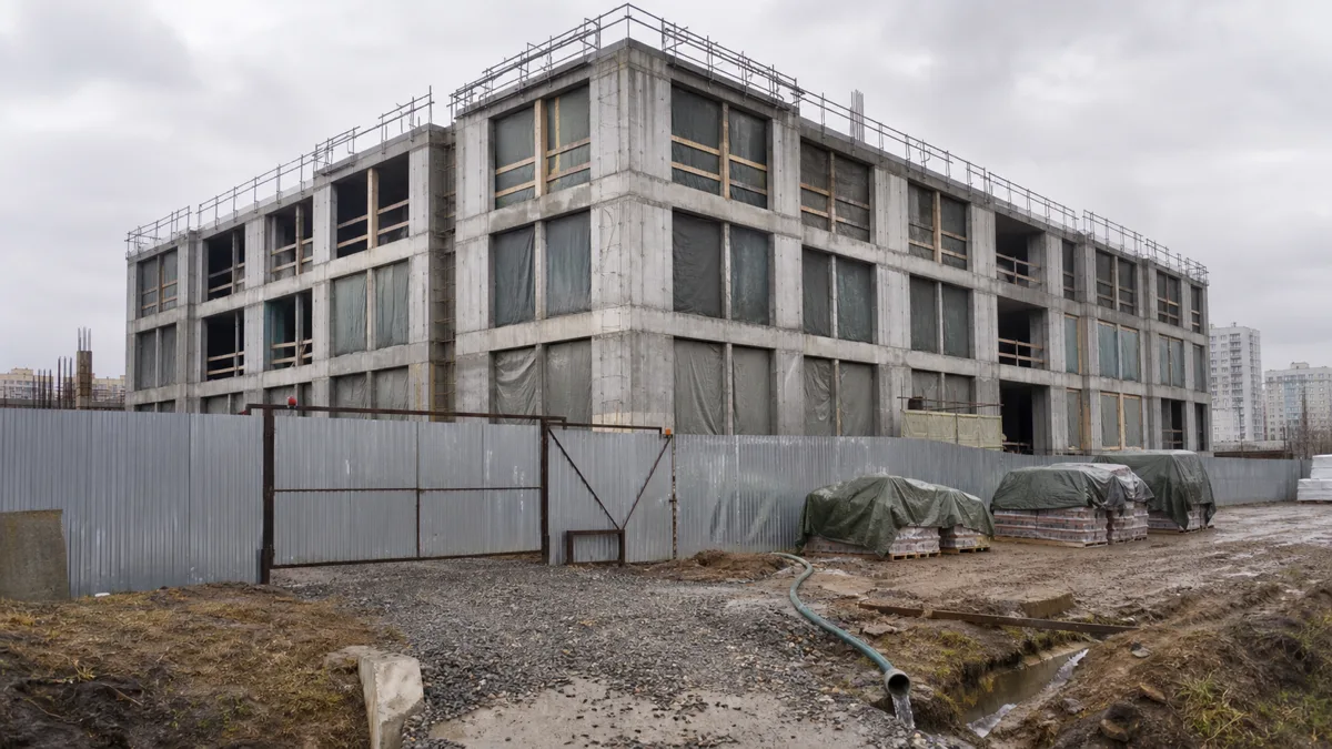 Законсервированное недостроенное здание с закрытыми проёмами, ограждением и водоотводом